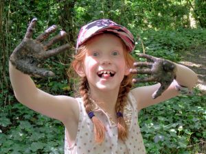 a girl smiling with mud on her hands